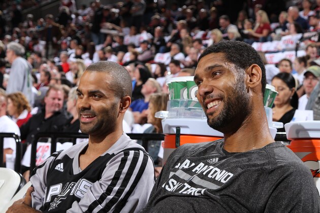 PORTLAND, OR - NOVEMBER 2: Tony Parker #9 and Tim Duncan #21 of the San Antonio Spurs smile and look on against the Portland Trailblazers on November 2, 2013 at the Moda Center Arena in Portland, Oregon. NOTE TO USER: User expressly acknowledges and agrees that, by downloading and or using this photograph, user is consenting to the terms and conditions of the Getty Images License Agreement. Mandatory Copyright Notice: Copyright 2013 NBAE (Photo by Sam Forencich/NBAE via Getty Images)