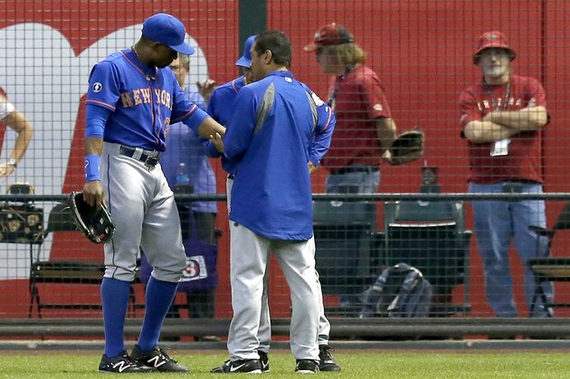New York Mets' Curtis Granderson (3) is looked at by Mets training staff after Granderson tried to make a play on a ball hit by Arizona Diamondbacks' Miguel Montero in the first inning of a baseball game on Monday, April 14, 2014, in Phoenix.  Granderson left the game early, but the Mets defeated the Diamondbacks 7-3. (AP Photo/Ross D. Franklin)