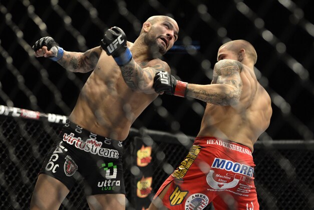 Apr 16, 2014; Quebec City, Quebec, Canada; Dustin Poirier (red  gloves) fights Akira Corassani (blue gloves) during their featherweight bout at Colisee Pepsi. Poirier won by KO/TKO. Mandatory Credit: Eric Bolte-USA TODAY Sports