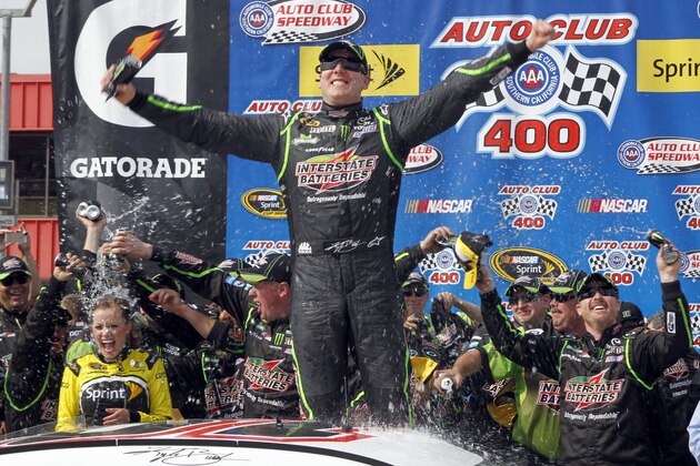 Kyle Busch, center, celebrates, as the team drenches his wife, Samantha Busch, left, in victory circle after winning the NASCAR Sprint Series auto race in Fontana, Calif., Sunday, March 23, 2014. (AP Photo/Alex Gallardo)