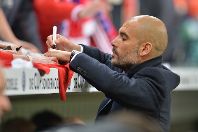 Munich head coach Pep Guardiola signs an autograph prior to the German soccer cup, DFB Pokal, semifinal  match between FC Bayern Munich and FC Kaiserslautern in the Allianz Arena in Munich, Germany, on Wednesday, April 16. 2014. (AP Photo/Kerstin Joensson)
