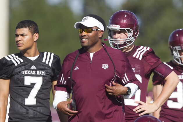 Texas A&M head coach Kevin Sumlin, center, smiles as he watches the team's NCAA college football practice, Monday, Aug, 5, 2013, in College Station, Texas. (AP Photo/Patric Schneider)