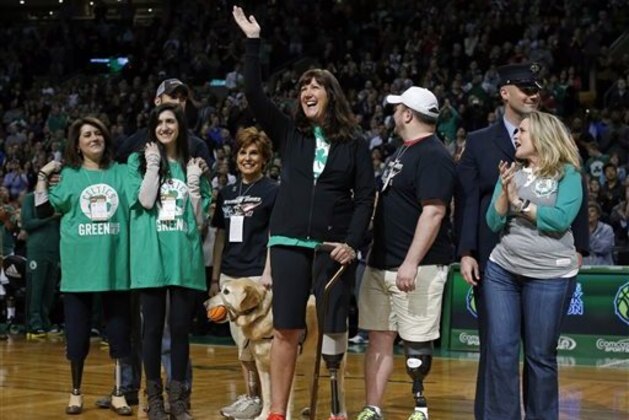 2013 Boston Marathon bombing survivor Karen Rand, center, waves to the cheering crowd as others injured in the blasts, Celeste Corcoran, left, and her daughter Sydney, second from left, and Roseann Sdoia, right, watch as they are honored during a break in an NBA basketball game between the Boston Celtics and the Washington Wizards in Boston, Wednesday, April 16, 2014. (AP Photo/Elise Amendola)
