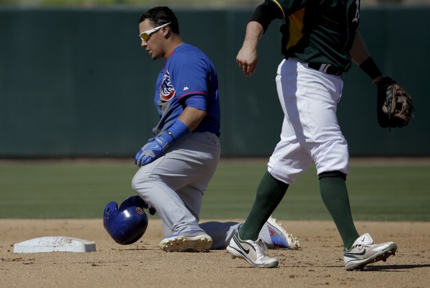 Oakland Athletics second baseman Eric Sogard, righrt, walks off after tagging out Chicago Cubs' Javier Baez stealing during the second inning of a baseball game in Phoenix, Monday, March 17, 2014. (AP Photo/Chris Carlson)