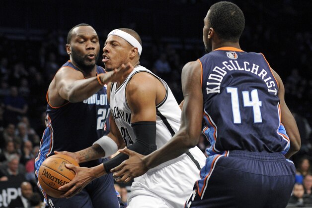 Brooklyn Nets' Paul Pierce splits the defense of Charlotte Bobcats' Al Jefferson, left, and Michael Kidd-Gilshrice, right, during the first quarter of an NBA basketball game Wednesday, March 19, 2014, at Barclay's Center in New York. (AP Photo/Bill Kostroun)