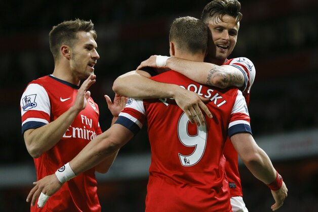Arsenal's Lukas Podolski, center, celebrates scoring a goal with teammates Aaron Ramsey, left, and Olivier Giroud, right, during the English Premier League soccer match between Arsenal and West Ham United at the Emirates stadium in London, Tuesday, April 15, 2014. (AP Photo/Kirsty Wigglesworth)