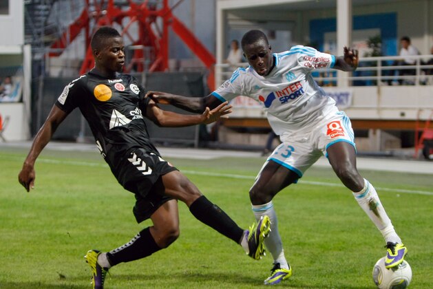 Stade de Reims' midfielder Prince Oniangue, left, challenges for the ball with Marseille's defender Benjamin Mendy during their League One soccer match, at the Velodrome Stadium, in Marseille, southern France, Saturday, Oct. 26, 2013. (AP Photo/Claude Paris)