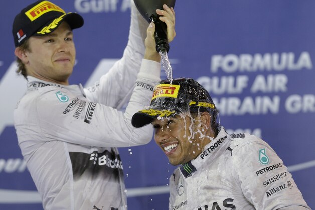 Mercedes driver Nico Rosberg of Germany, left, second place, sprays rose water to the winner teammate Mercedes driver Lewis Hamilton of Britain on the podium after the Bahrain Formula One Grand Prix at the Bahrain International Circuit in Sakhir, Bahrain, Sunday, April 6, 2014. (AP Photo/Luca Bruno)