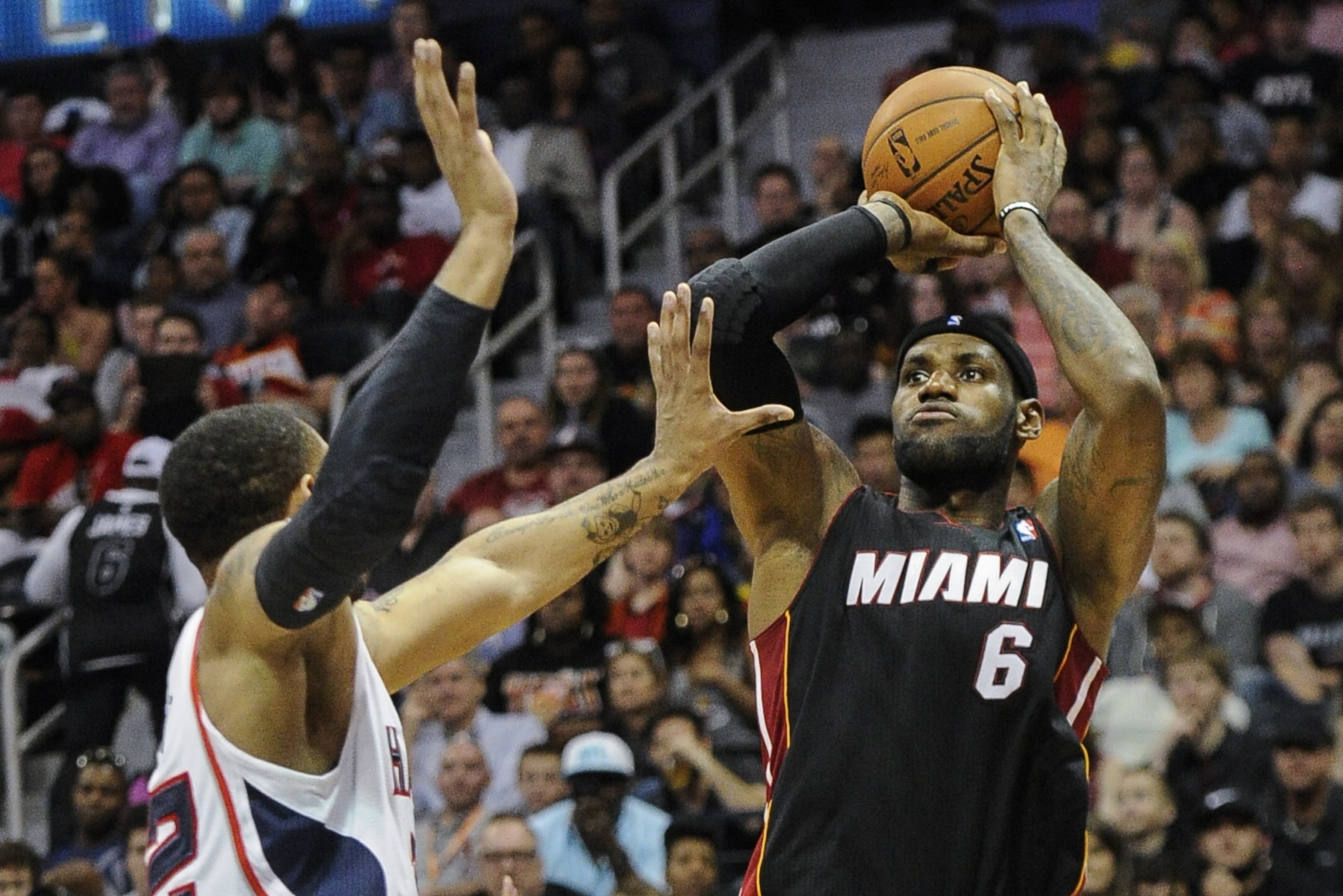 Miami Heat forward LeBron James (6) puts up a jump shot defended by Atlanta Hawks forward Mike Scott (32) during the second half of an NBA basketball game, Saturday, April 12, 2014, in Atlanta. Atlanta won 98-85. (AP Photo/John Amis)