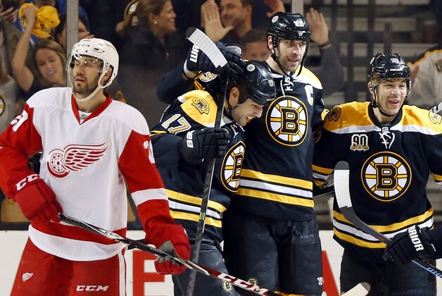 Detroit Red Wings' Drew Miller skates away as Boston Bruins' Jarome Iginla, right, Milan Lucic (17) and Zdeno Chara celebrate after Chara scored during the third period of Boston's 4-1 win in Game 2 of a first-round NHL hockey playoff series in Boston Sunday, April 20, 2014. (AP Photo/Winslow Townson)