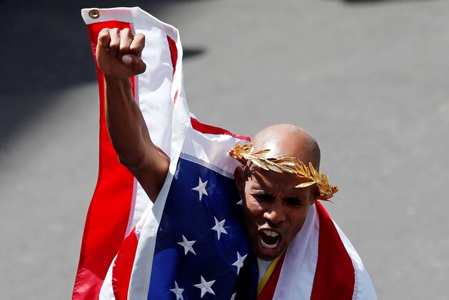 Apr 21, 2014; Boston, MA, USA; Meb Keflezighi (USA) pumps his fist while wearing an American flag at the finish line after winning the men's division of the 2014 Boston Marathon. Mandatory Credit: Greg M. Cooper-USA TODAY Sports