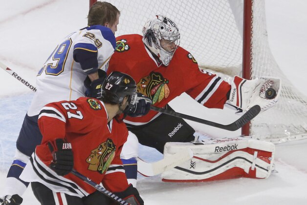 Chicago Blackhawks goalie Corey Crawford (50) makes a glove save on a shot by St. Louis Blues center Steve Ott (29) as Johnny Oduya (27) watches during the first period in Game 3 of a first-round NHL hockey Stanley Cup playoff series game Monday, April 21, 2014, in Chicago. (AP Photo/Charles Rex Arbogast)
