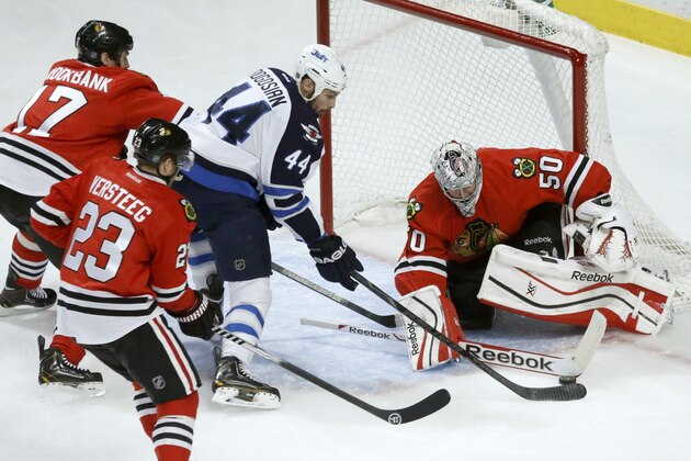 Chicago Blackhawks goalie Corey Crawford (50) makes a save on a shot by Winnipeg Jets defenseman Zach Bogosian (44) as Sheldon Brookbank (17) and Kris Versteeg (23) defend during the first period of an NHL hockey game Sunday, Jan. 26, 2014, in Chicago. (AP Photo/Charlie Arbogast)