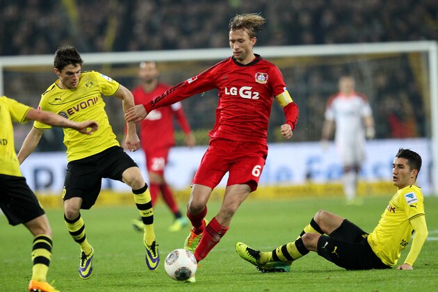Dortmund's Nuri Sahin, right, and Erik Durm, left challange for the ball with Leverkusen's Simon Rolfes during the German first division Bundesliga soccer match between Borussia Dortmund and Bayer Leverkusen in Dortmund, Germany, Saturday, Dec. 7, 2013. (AP Photo/Michael Probst)