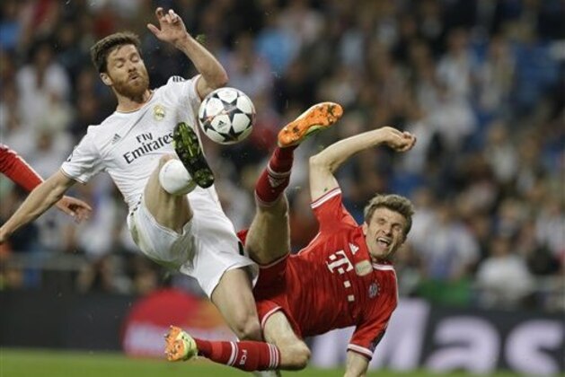 Real's Xabi Alonso, left, and Bayern's Thomas Mueller challenge for the ball during a  Champions League semifinal first leg soccer match between Real Madrid and Bayern Munich at the Santiago Bernabeu stadium in Madrid, Spain, Wednesday, April 23, 2014 .(AP Photo/Paul White)