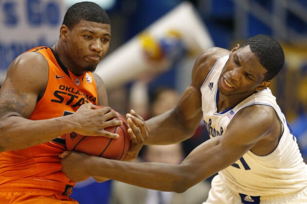 Oklahoma State guard Marcus Smart (33) and Kansas center Joel Embiid (21) battle to a jump ball during the second half of an NCAA college basketball game at Allen Fieldhouse in Lawrence, Kan., Saturday, Jan. 18, 2014. Kansas defeated Oklahoma State 80-78. (AP Photo/Orlin Wagner)