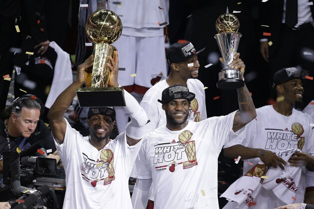 The Miami Heat's Dwyane Wade, left, holds the Larry O'Brien NBA Championship Trophy as  LeBron James holds his Bill Russell NBA Finals Most Valuable Player Award after Game 7 of the NBA basketball championship against the San Antonio Spurs, Friday, June 21, 2013, in Miami. The Miami Heat defeated the San Antonio Spurs 95-88 to win their second straight NBA championship. The Miami Heat's Chris Bosh celebrates in the background. (AP Photo/Wilfredo Lee)