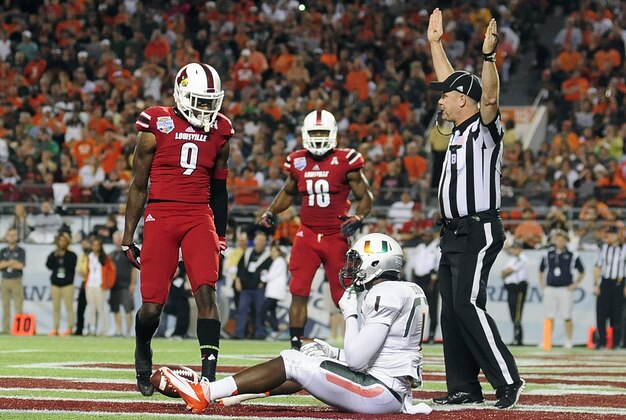Dec 28, 2013; Orlando, FL, USA; Louisville Cardinals wide receiver DeVante Parker (9) stands over Miami Hurricanes defensive back Artie Burns (1) after a touchdown catch in the second quarter in the Russell Athletic Bowl at Florida Citrus Bowl Stadium. Mandatory Credit: David Manning-USA TODAY Sports
