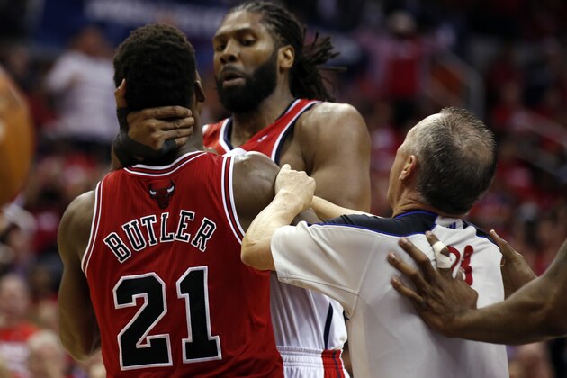 Referee Jason Phillips moves to separate Chicago Bulls guard Jimmy Butler (21) and Washington Wizards forward Nene, center, from Brazil, in the second half of Game 3 of an opening-round NBA basketball playoff series on Friday, April 25, 2014, in Washington. Nene received a double technical and was ejected. The Bulls won 100-97. (AP Photo/Alex Brandon)