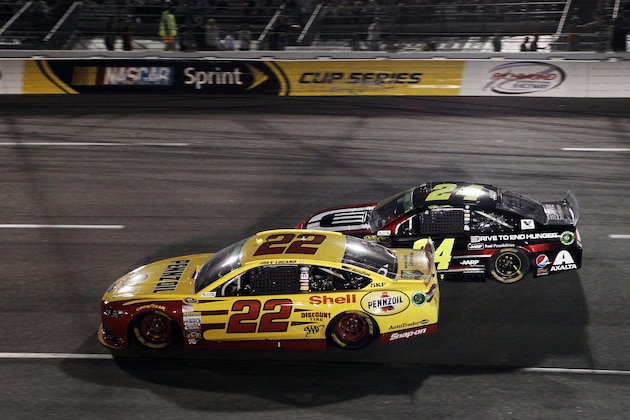 Apr 26, 2014; Richmond, VA, USA; NASCAR Sprint Cup driver Joey Logano (22) passes NASCAR Sprint Cup driver Jeff Gordon (24) for the lead during the Toyota Owners 400 at Richmond International Raceway. Mandatory Credit: Peter Casey-USA TODAY Sports