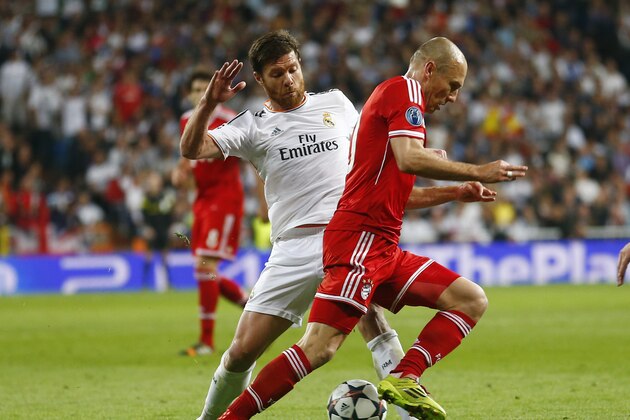 Real's Xabi Alonso stops Bayern's Arjen Robben, right, during a  Champions League semifinal first leg soccer match between Real Madrid and Bayern Munich at the Santiago Bernabeu stadium in Madrid, Spain, Wednesday, April 23, 2014. (AP Photo/Paul White)
