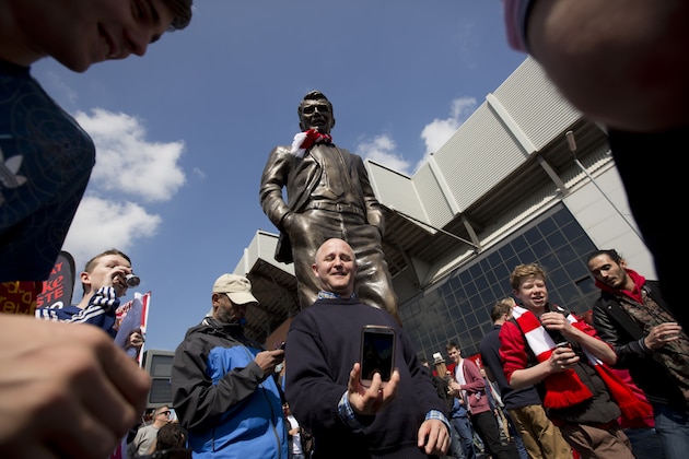Supporters gather around a statue mocking former Manchester United manager David Moyes before Liverpool's English Premier League soccer match against Chelsea at Anfield Stadium, Liverpool, England, Sunday April 27, 2014. (AP Photo/Jon Super)