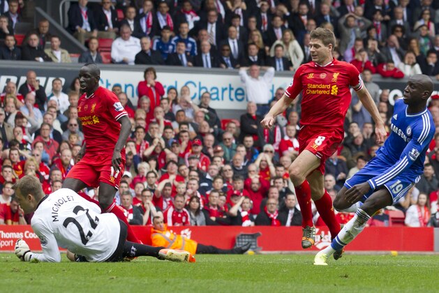 Chelsea's Demba Ba, right, scores past Liverpool goalkeeper Simon Mignolet, below, after an error by captain Steven Gerrard, second right, during their English Premier League soccer match at Anfield Stadium, Liverpool, England, Sunday April 27, 2014. (AP Photo/Jon Super)