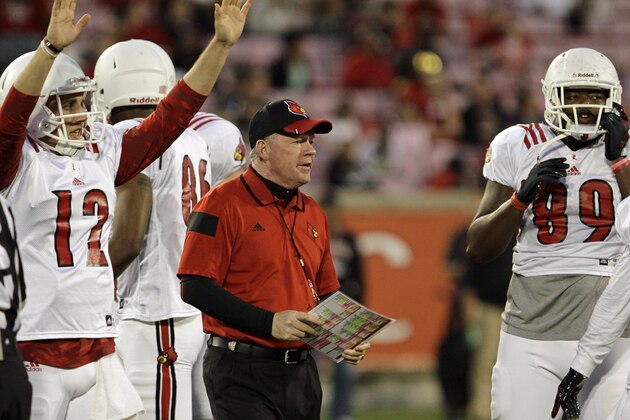 New Louisville coach Bobby Petrino, center, waits for his squad to huddle during a break in the annual Red-White NCAA college spring football game in Louisville, Ky., Friday, April 11, 2014. At left is quarterback Brett Nelson (12).  (AP Photo/Garry Jones)