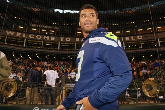 SEATTLE, WA - APRIL 08:  Quarterback Russell Wilson of the Seattle Seahawks walks onto the field before throwing out the ceremonial first pitch prior to the game between the Los Angeles Angels of Anaheim and the Seattle Mariners on Opening Day at Safeco Field on April 8, 2014 in Seattle, Washington.  (Photo by Otto Greule Jr/Getty Images)