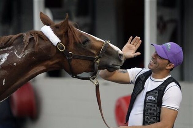 Exercise rider William Delgado plays with Kentucky Derby hopeful California Chrome after a morning workout at Churchill Downs Wednesday, April 30, 2014, in Louisville, Ky. (AP Photo/Garry Jones)