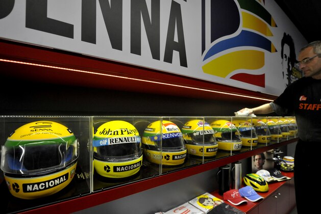A man cleans helmets belonged to late Brazilian driver Ayrton Senna on display at the the Imola track, Italy, Wednesday, April 30, 2014. Fans and family members are gathering this week to pay their respects to former Formula One drivers Ayrton Senna and Roland Ratzenberger on the 20th anniversary of their deaths. F1 drivers' chaplain Sergio Mantovani celebrated a memorial mass Wednesday in a packed room beside pit lane at the Enzo and Dino Ferrari track that once hosted the San Marino Grand Prix. (AP Photo/Marco Vasini)