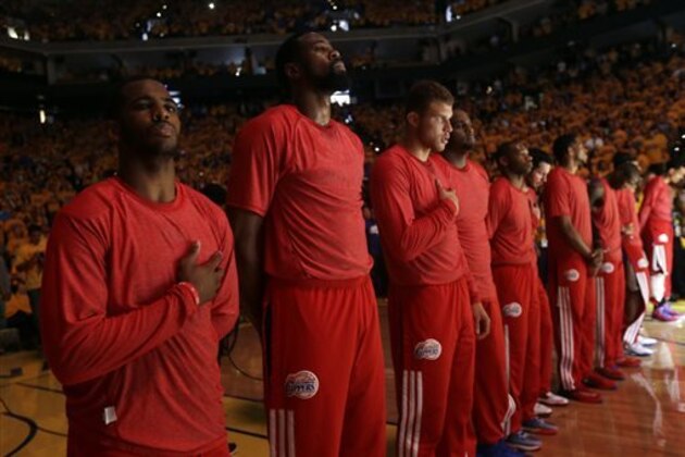 Members of the Los Angeles Clippers listen to the national anthem before Game 4 of an opening-round NBA basketball playoff series against the Golden State Warriors on Sunday, April 27, 2014, in Oakland, Calif. The Clippers chose not to speak publicly about owner Donald Sterling. Instead, they made a silent protest. The players wore their red Clippers' warmup shirts inside out to hide the team's logo. (AP Photo/Marcio Jose Sanchez)