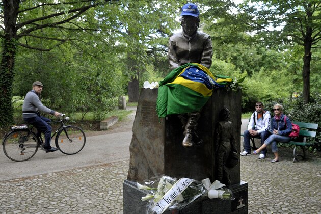 A Brazilian flag and flowers adorn a statue of Ayrton Senna, in a park close to the Imola track, Italy, Wednesday, April 30, 2014. It is a testament to Ayrton Senna's lasting impact on Formula One that the 20th anniversary of his death will be observed this week with five days of commemorations at the Imola track where he had his fatal accident. Current and past F1 drivers, mechanics, racing officials and fans will pay their respects to Senna and Austrian driver Roland Ratzenberger, who also died at the 1994 San Marino Grand Prix. (AP Photo/Marco Vasini)