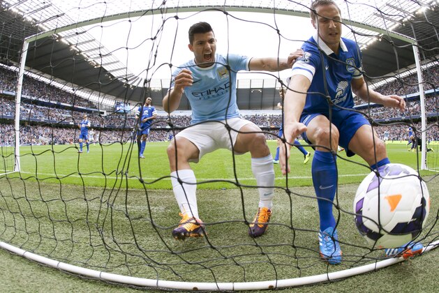 Manchester City's Sergio Aguero, centre, celebrates as he runs into the goal to retrieve the ball alongside Everton's Philip Jagielka after a goal by his teammate Alvaro Negredo, during their English Premier League soccer match at the Etihad Stadium, Manchester, England, Saturday Oct. 5, 2013. (AP Photo/Jon Super)