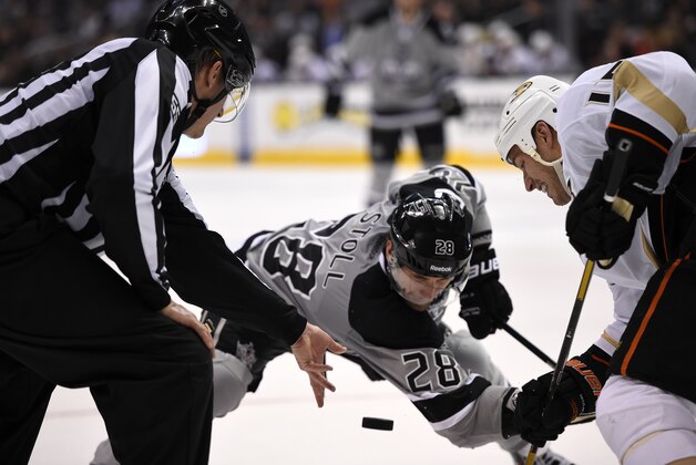 Los Angeles Kings center Jarret Stoll, center, and Anaheim Ducks center Ryan Getzlaf face off as a linesman drops the puck during the second period of an NHL hockey game, Saturday, April 12, 2014, in Los Angeles.  (AP Photo/Mark J. Terrill)