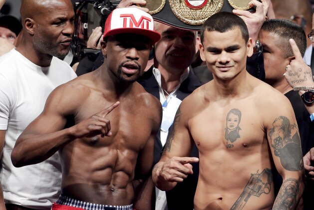 Floyd Mayweather Jr., left, poses on the scales with Marcos Maidana during the official weigh-in at the MGM Grand Hotel in Las Vegas, Friday, May 2, 2014. Mayweather is to face Maidana in a welterweight title fight on Saturday. (AP Photo/Chris Carlson)