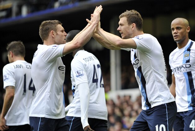 Manchester City's Edin Dzeko, right, celebrates with teammate James Milner after scoring the second goal of the game during their English Premier League soccer match against Everton at Goodison Park in Liverpool, England, Saturday May 3, 2014. (AP Photo/Clint Hughes)
