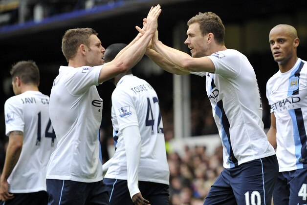 Manchester City's Edin Dzeko, right, celebrates with teammate James Milner after scoring the second goal of the game during their English Premier League soccer match against Everton at Goodison Park in Liverpool, England, Saturday May 3, 2014. (AP Photo/Clint Hughes)