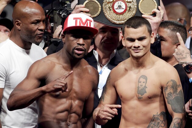 Floyd Mayweather Jr., left, poses on the scales with Marcos Maidana during the official weigh-in at the MGM Grand Hotel in Las Vegas, Friday, May 2, 2014. Mayweather is to face Maidana in a welterweight title fight on Saturday. (AP Photo/Chris Carlson)