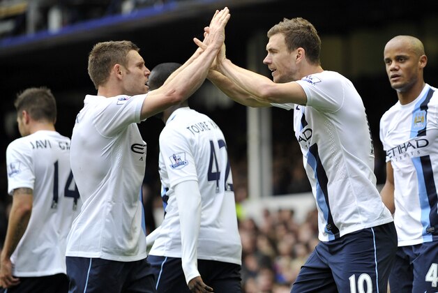 Manchester City's Edin Dzeko, right, celebrates with teammate James Milner after scoring the second goal of the game during their English Premier League soccer match against Everton at Goodison Park in Liverpool, England, Saturday May 3, 2014. (AP Photo/Clint Hughes)