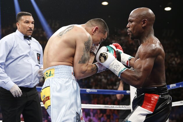 Floyd Mayweather Jr., right, trades blows with Marcos Maidana, from Argentina, in their WBC-WBA welterweight title boxing fight Saturday, May 3, 2014, in Las Vegas. Referee Tony Weeks is at left. (AP Photo/Eric Jamison)