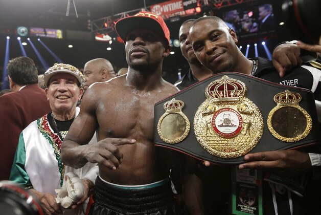 Floyd Mayweather Jr., center, poses with his corner and a champion's belt after his WBC-WBA welterweight title boxing fight against Marcos Maidana Saturday, May 3, 2014, in Las Vegas. Mayweather won the bout by majority decision. (AP Photo/Isaac Brekken)