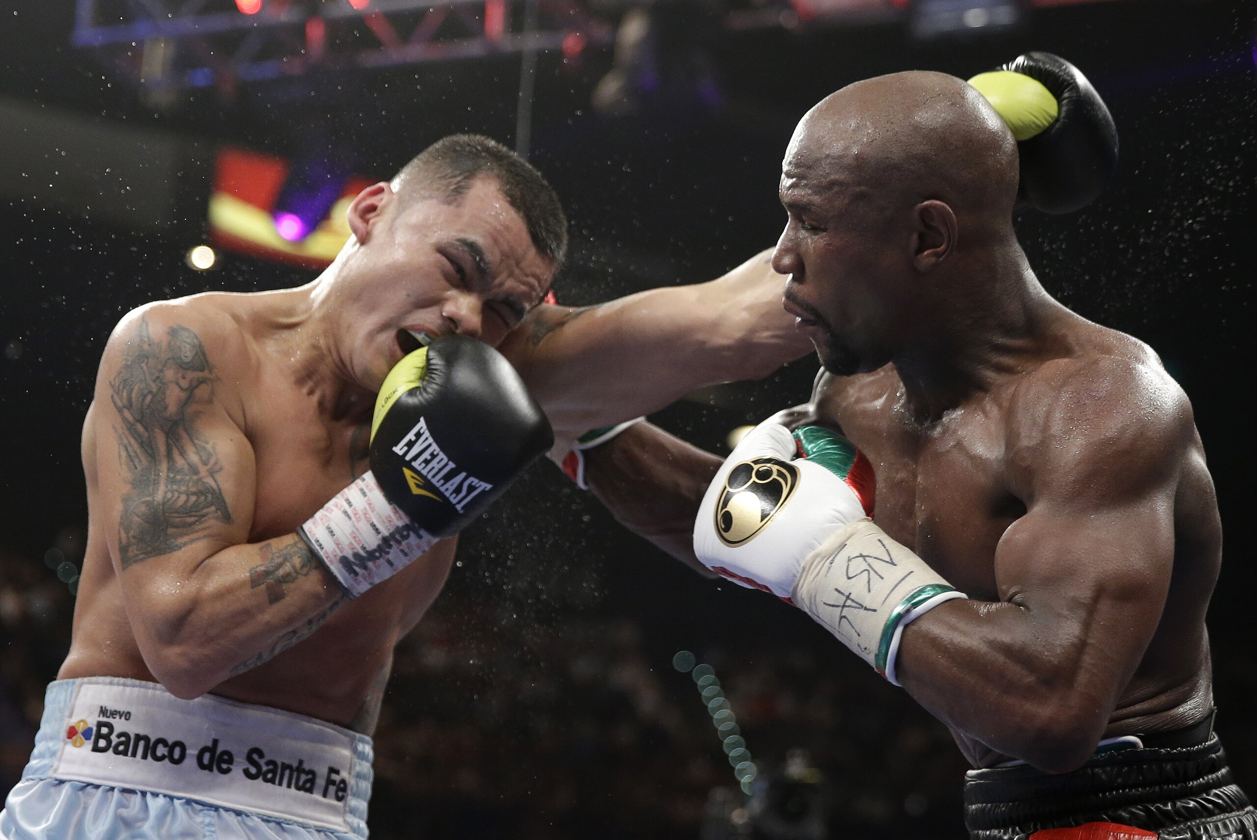 Marcos Maidana, left, from Argentina, trades blows with Floyd Mayweather Jr. in their WBC-WBA welterweight title boxing fight Saturday, May 3, 2014, in Las Vegas. Mayweather won the bout by majority decision. (AP Photo/Isaac Brekken)