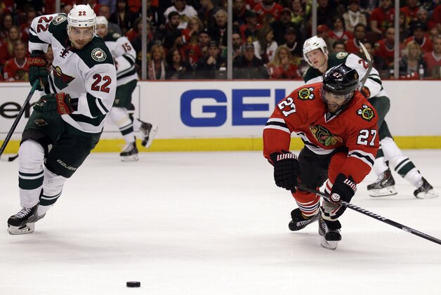 Chicago Blackhawks' Johnny Oduya (27), right, chases the puck against Minnesota Wild's Nino Niederreiter (22) during the first period  in Game 1 of an NHL hockey second-round playoff series in Chicago, Friday, May 2, 2014. (AP Photo/Nam Y. Huh)
