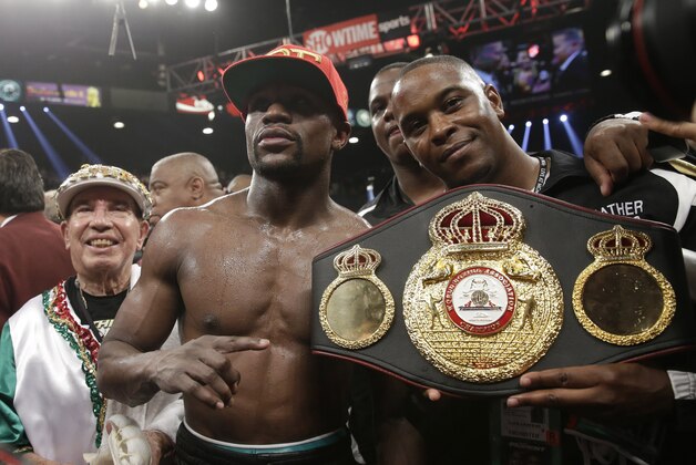 Floyd Mayweather Jr., center, poses with his corner and a champion's belt after his WBC-WBA welterweight title boxing fight against Marcos Maidana Saturday, May 3, 2014, in Las Vegas. Mayweather won the bout by majority decision. (AP Photo/Isaac Brekken)