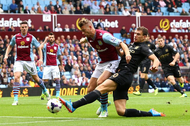 BIRMINGHAM, ENGLAND - SEPTEMBER 28:  Edin Dzeko of Manchester City takes a shot at goal under pressure from Nathan Baker of Aston Villa during the Barclays Premier League match between Aston Villa and Manchester City at Villa Park on September 28, 2013 in Birmingham, England.  (Photo by Jan Kruger/Getty Images)