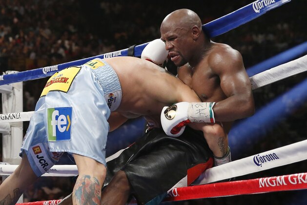 Floyd Mayweather Jr., right, is driven through the ropes by Marcos Maidana in their WBC-WBA welterweight title boxing fight Saturday, May 3, 2014, in Las Vegas. Mayweather won the bout by majority decision.  (AP Photo/Eric Jamison)