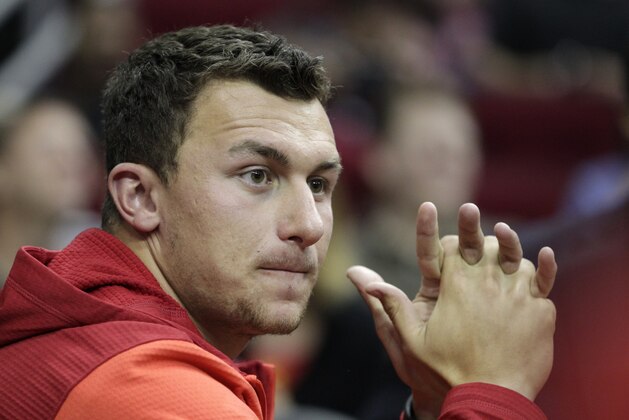 Texas A&M quarterback Johnny Manziel watches as the Houston Rockets take on the Minnesota Timberwolves during an NBA basketball game , Thursday, March 20, 2014, in Houston. (AP Photo/Patric Schneider)