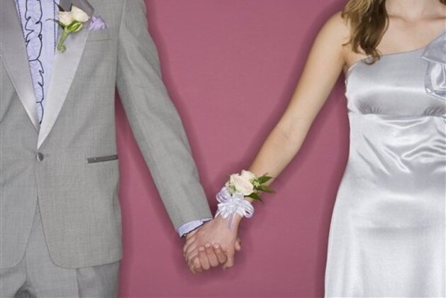 Couple in prom attire holding hands (Photo by: Tetra Images/AP Images)
