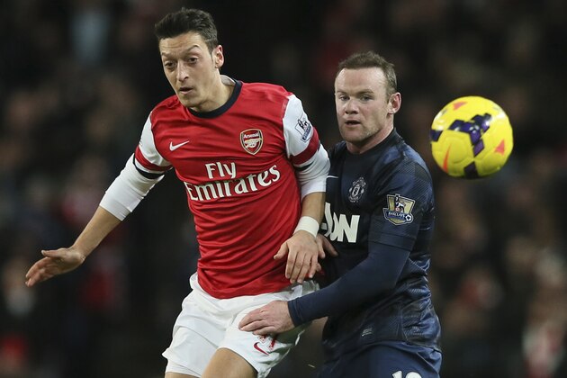 FILE - In this Feb. 12, 2014, file photo, Arsenal's Mesut Ozil, left, nudges the ball from Manchester United's Wayne Rooney during their English Premier League soccer match in London. Less than a year after pushing to leave Manchester United, Rooney committed his long-term future to the struggling Premier League champion on Friday, Feb. 21, by signing a lucrative contract through June 2019. (AP Photo/Alastair Grant, File)